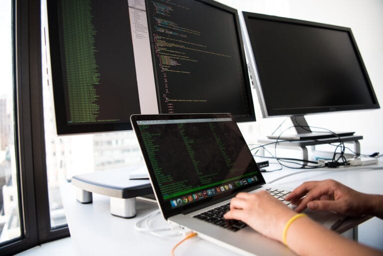 A developer's desk setup with multiple monitors displaying code and technical diagrams, illustrating a focused work session on programming.